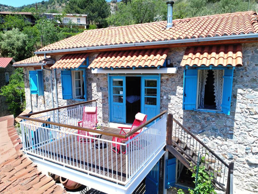 a stone house with blue doors and red chairs on a balcony at Kalopanayiotis Cottage in Kalopanayiotis