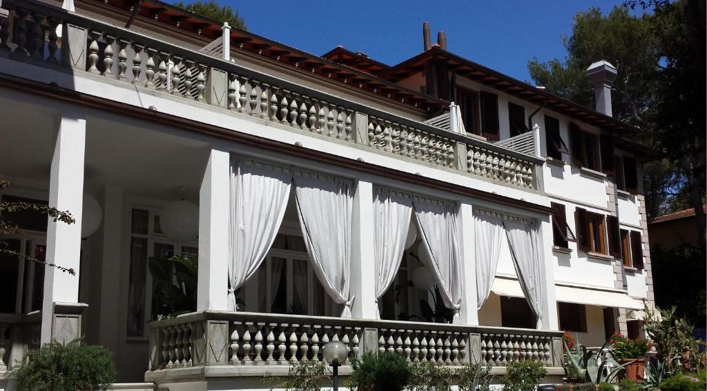 a white building with white curtains on the balcony at Hotel Tirreno in Castiglioncello