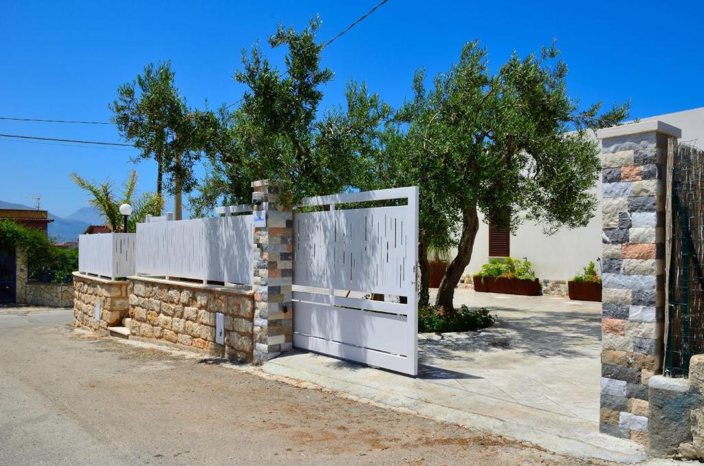 a white door on a stone wall next to a tree at Villa con piscina Alcamo Marina in Alcamo