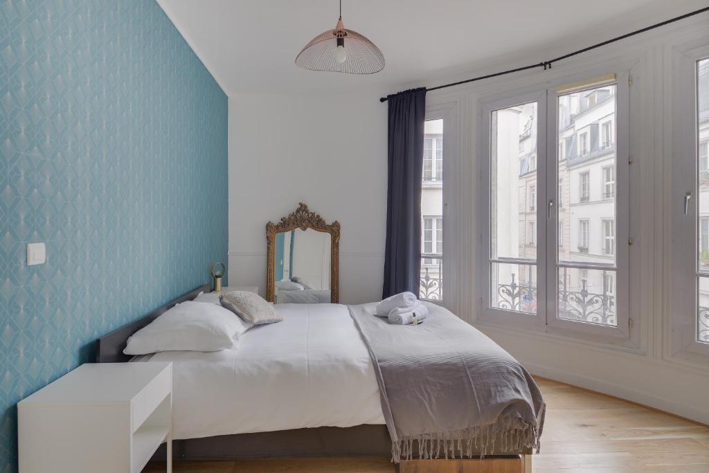 Lovely Parisian Flat - Louvre rue St Honoré في باريس: غرفة نوم بسرير مع جدار ازرق