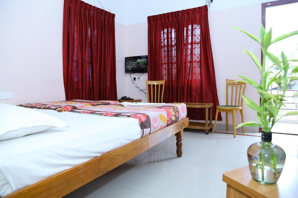 1 dormitorio con 1 cama y cortinas rojas en princess inn royal, en Trivandrum