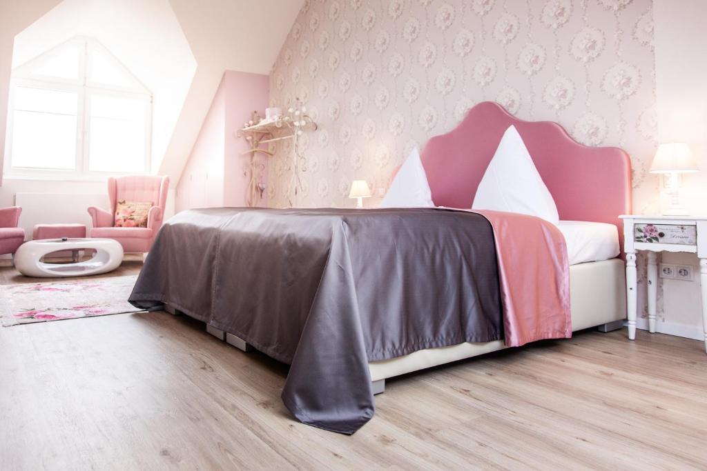 a bedroom with a large bed with a pink headboard at Hotel Wulff in Bad Sassendorf