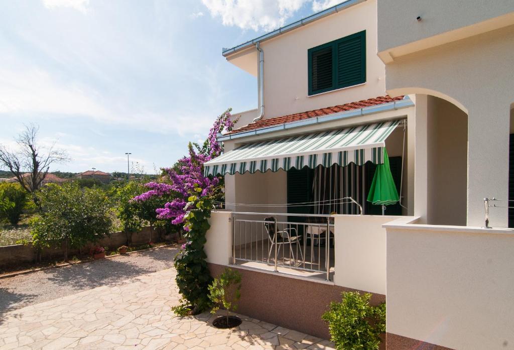 a house with a balcony with a table and purple flowers at Apartmani Stjepan in Vinišće