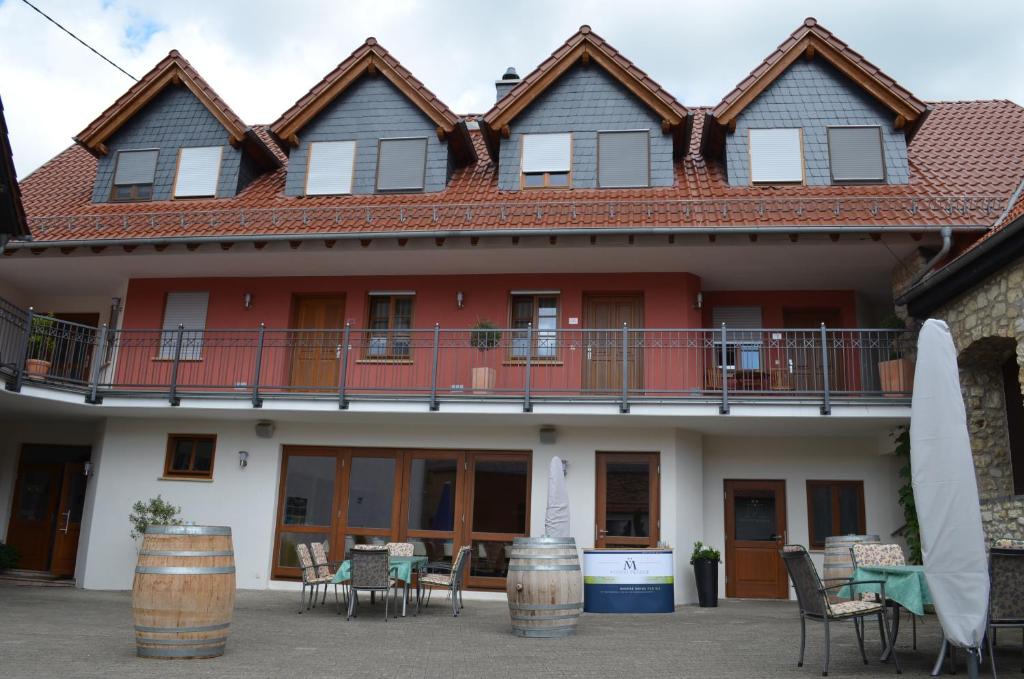 a large house with a balcony and tables and chairs at Hofgut Metzler in Gau-Heppenheim