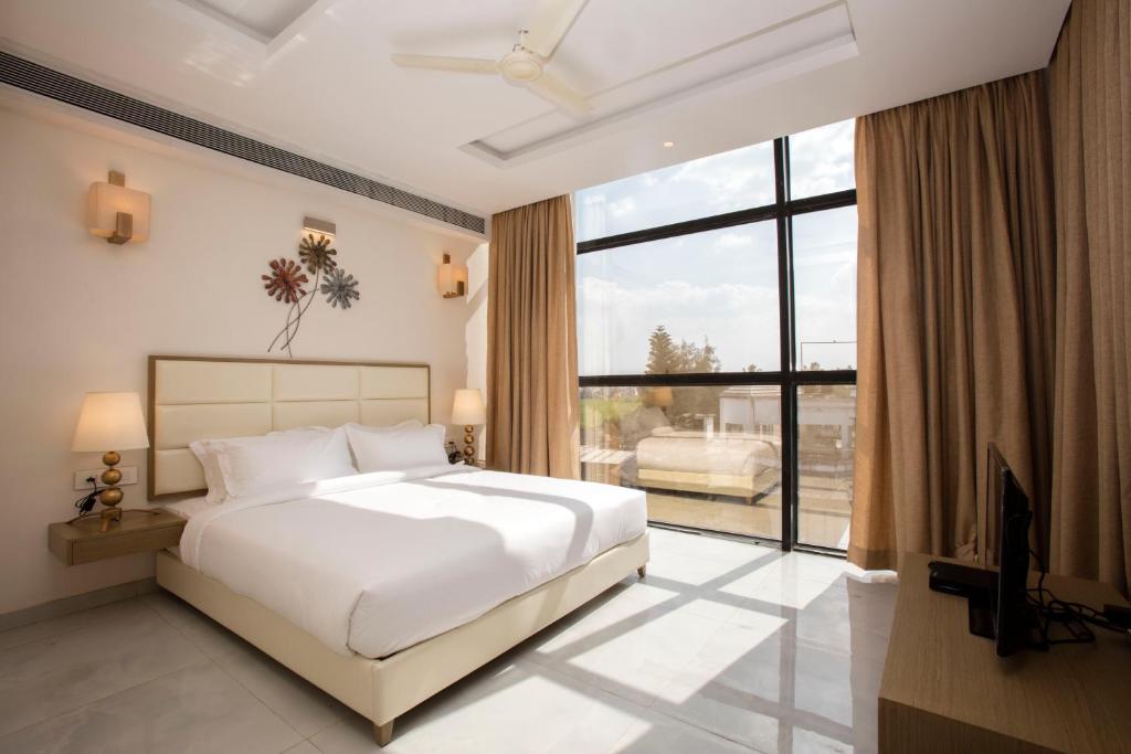 a bedroom with a white bed and a large window at Sapphire Premium Hotel & Suite in Karād