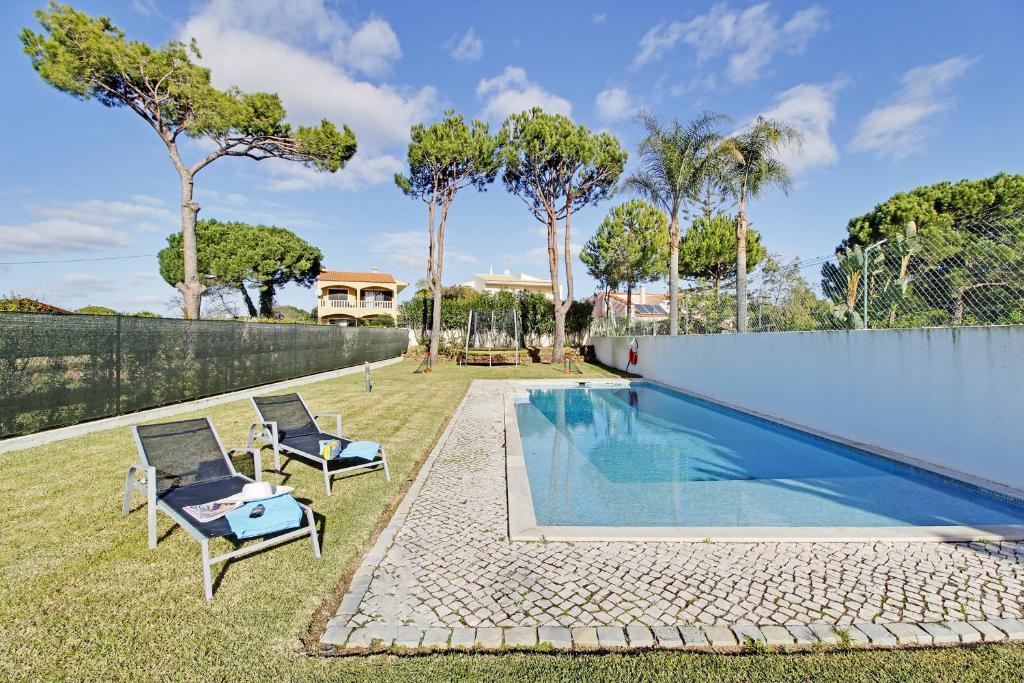 una piscina in un cortile con due sedie e una recinzione di Villa Argentina a Vilamoura