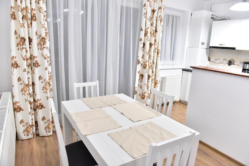 ein weißes Esszimmer mit einem weißen Tisch und Stühlen in der Unterkunft Sibiu City Residence in Sibiu