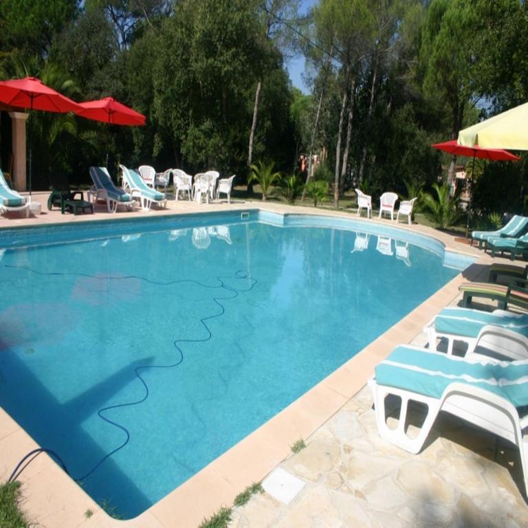 une grande piscine avec chaises et parasols dans l'établissement A la Verte Campagne - Appartements / Gîtes, à Roquebrune-sur Argens