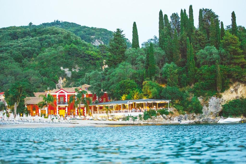 a resort on the shore of a beach with trees at Villa Rossa in Parga