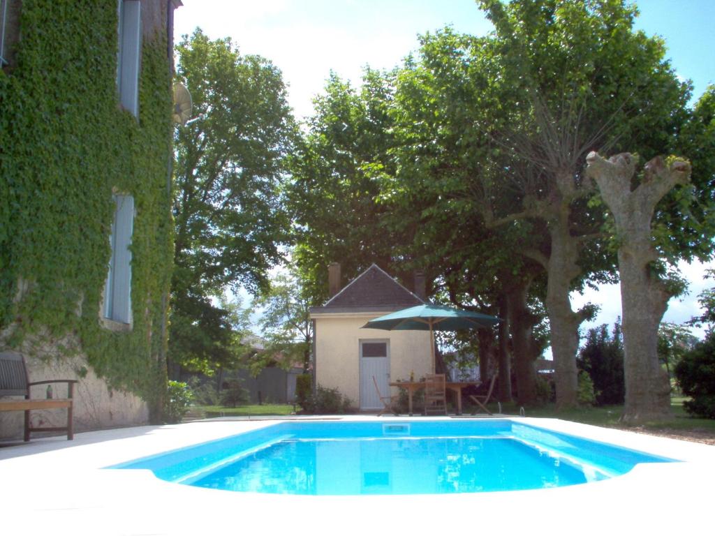 a swimming pool with an umbrella next to a building at Château des Grandes Vignes in Preignac