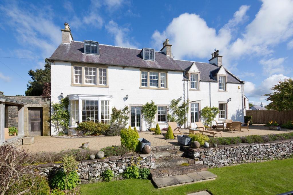 ein großes weißes Haus mit einer Steinmauer in der Unterkunft Bowden House B&B in Melrose