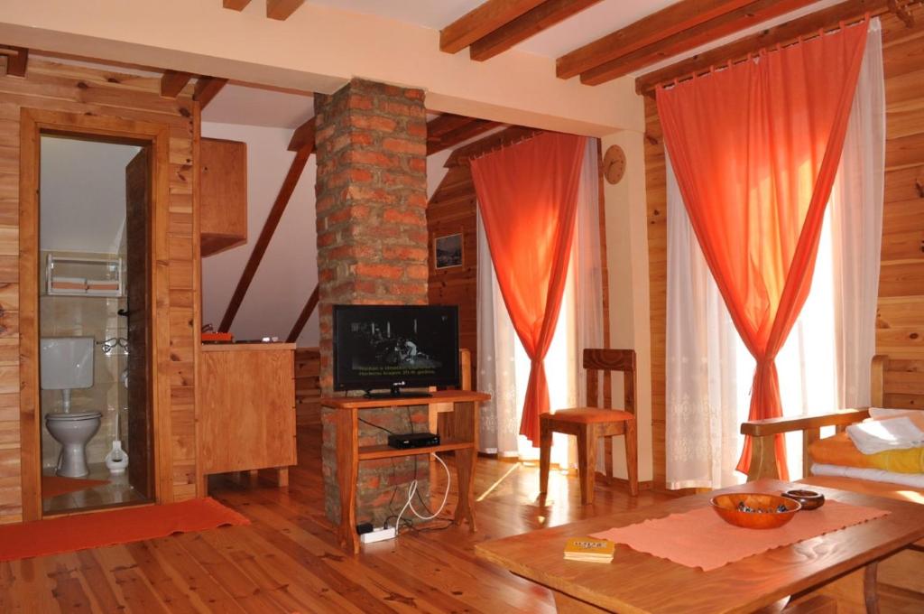 sala de estar con cortinas rojas y TV en Dana apartmani, en Kolašin
