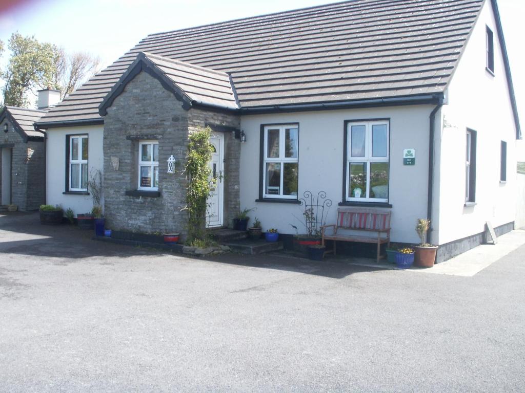 a white house with a red bench in front of it at Toomullin House Accommodation in Doolin