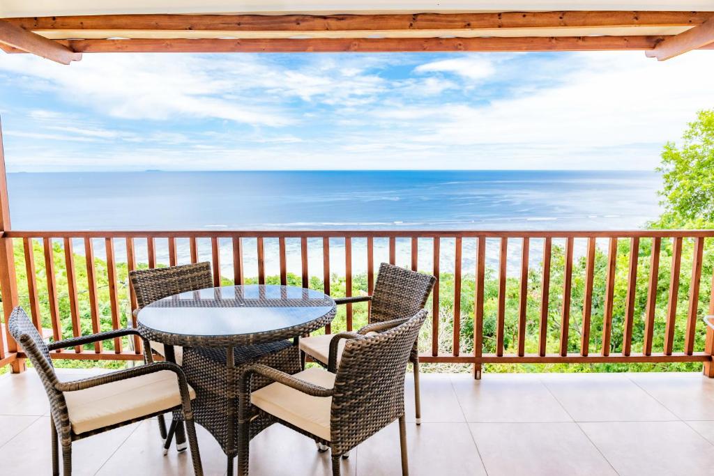 a patio with a table and chairs on a balcony at Villa Lima in Mahe
