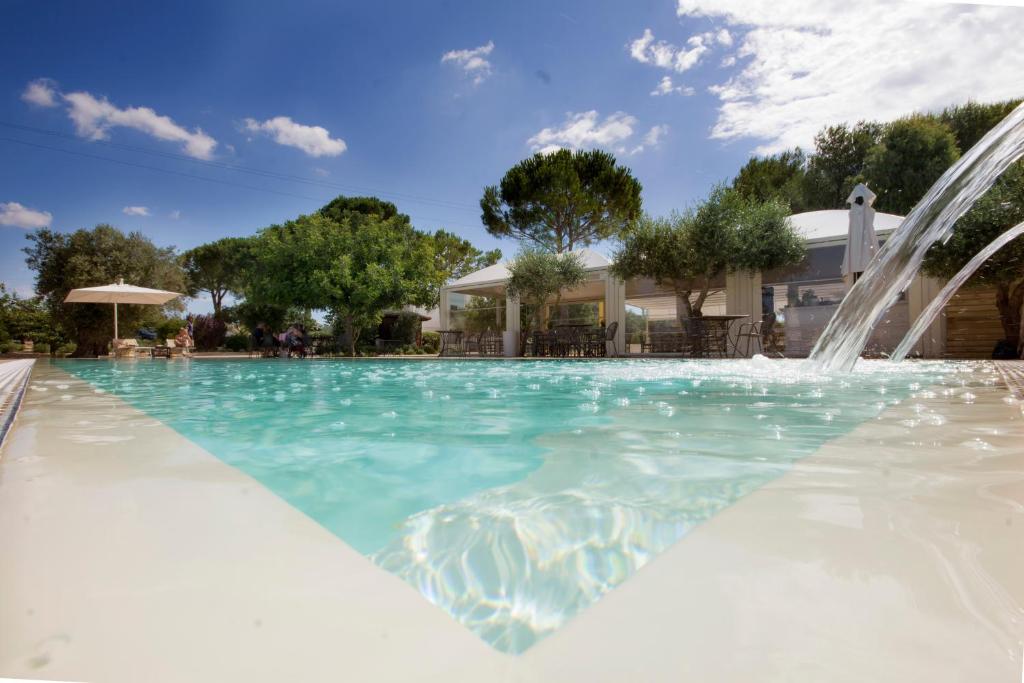 una piscina con fontana di fronte a una casa di Hotel Garden Salento a Torre Vado