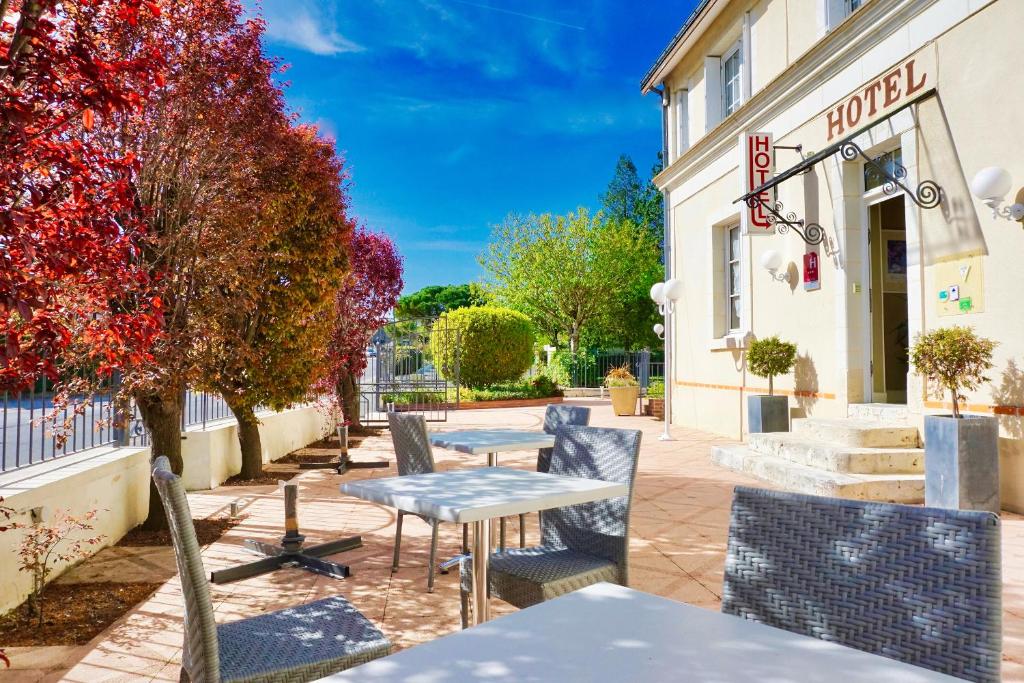 un patio con tavoli e sedie di fronte a un hotel di Logis Hôtel Restaurant Clair Cottage, Chisseaux - Chenonceaux a Chisseaux