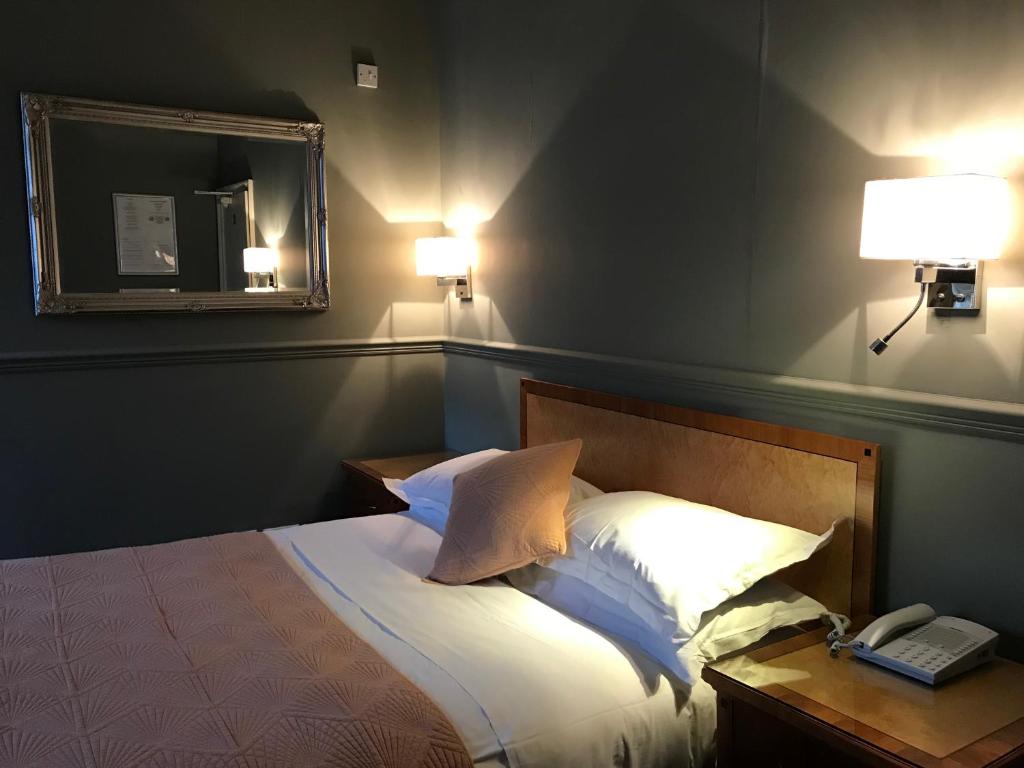 a bedroom with a bed with a mirror and a phone at Eurobar & Hotel in Oxford