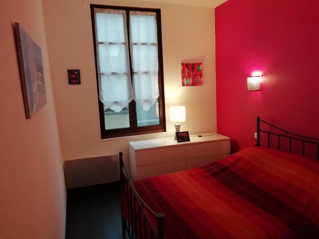 um quarto vermelho com uma cama e uma janela em La Perle du Rouergue em Villefranche-de-Rouergue