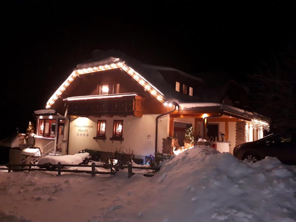 Una casa cubierta de nieve por la noche con luces. en Lungau Apartment - Ferienwohnung Haus Esl, en Hintergöriach