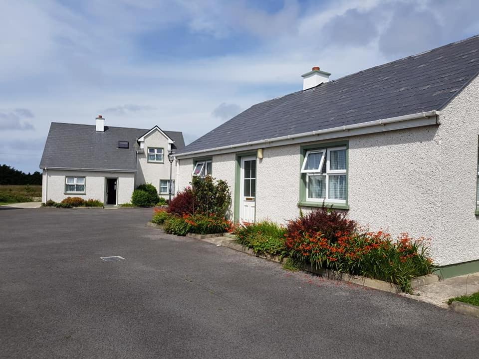 a white house with a lot of flowers in the driveway at Fairgreen Cottages in Dungloe