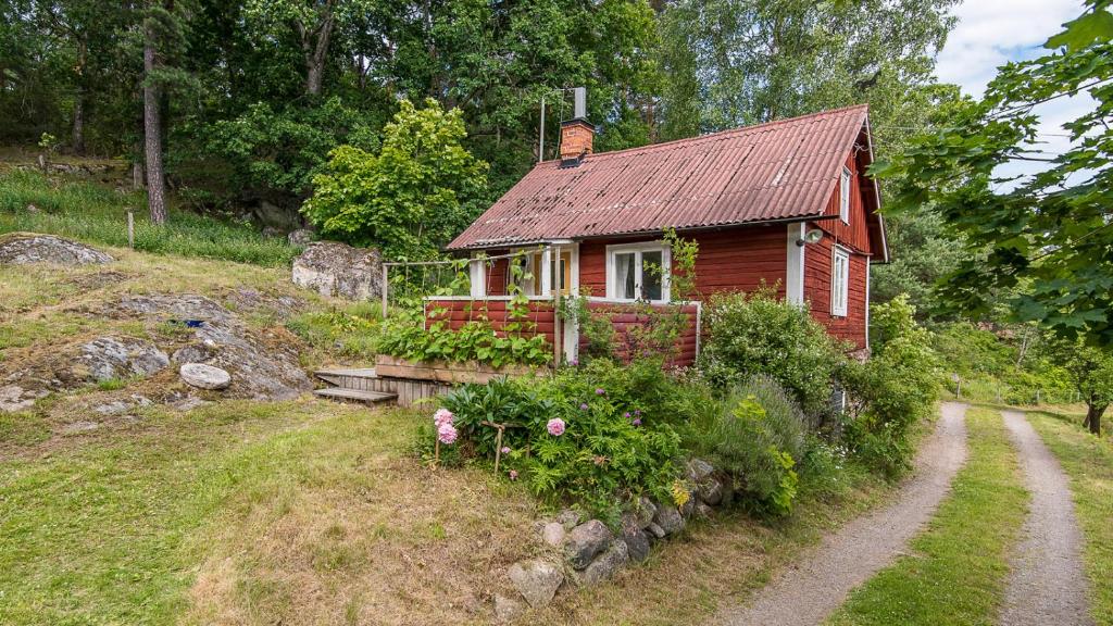 18th century farm cottage في فالديمارشفيك: منزل احمر صغير على جانب تل