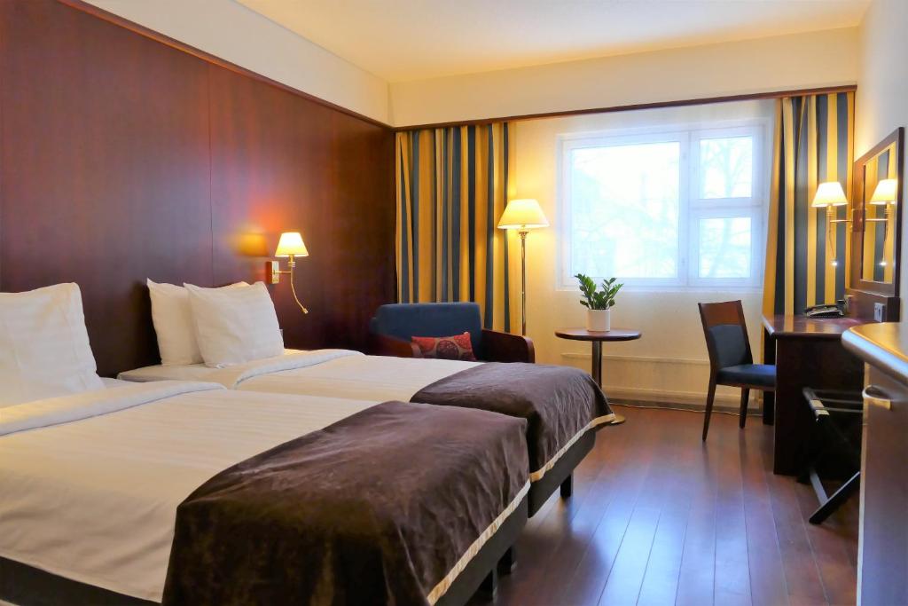 una camera d'albergo con 2 letti e una scrivania di Hotel Kalliohovi a Rauma