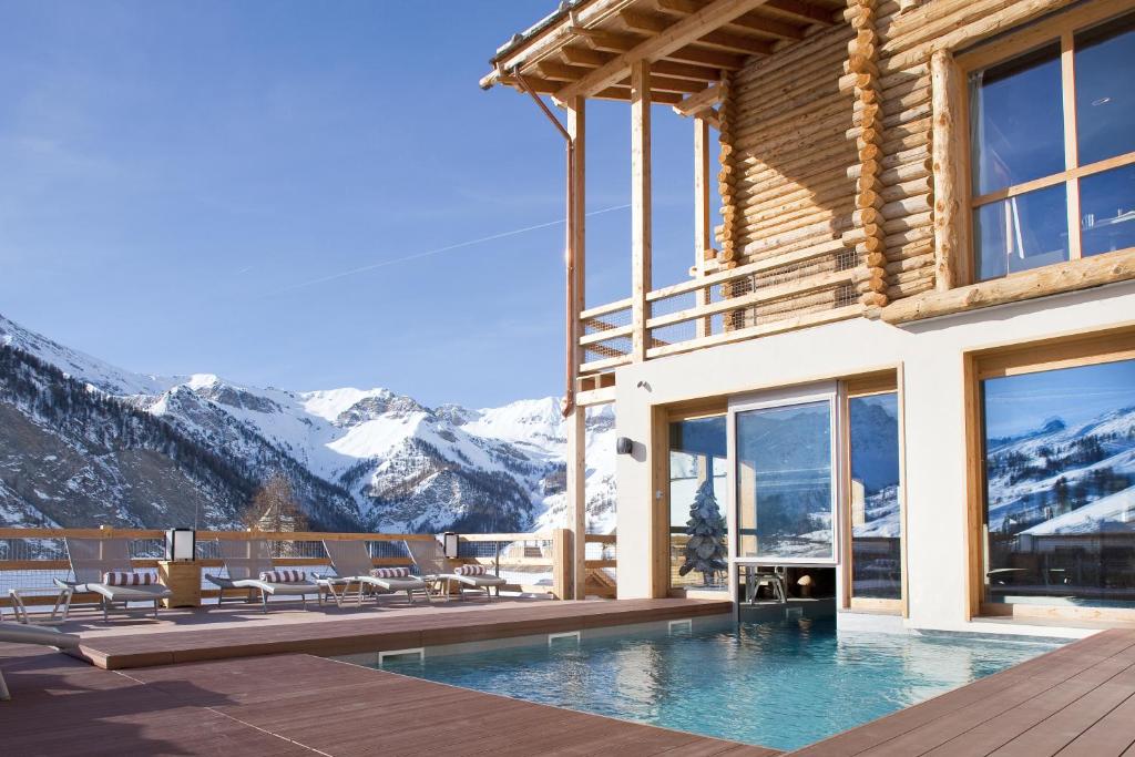 a house with a swimming pool and mountains at Hôtel & Spa L'Alta Peyra in Saint-Véran