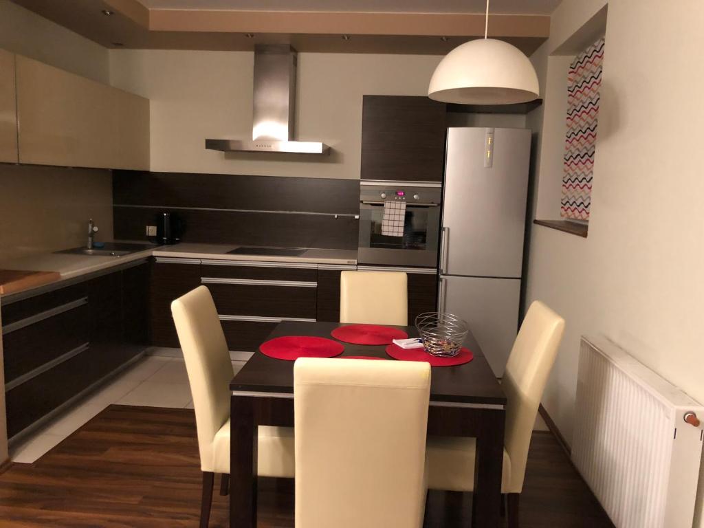 uma cozinha com uma mesa com cadeiras e um frigorífico em Apartamenty Tychy Bielska 145 em Tychy