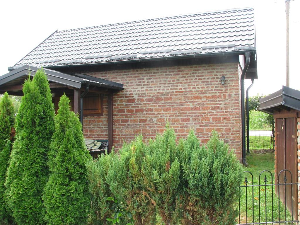 a brick house with a fence and some bushes at Cottage Plavi Lav Potok in Potok