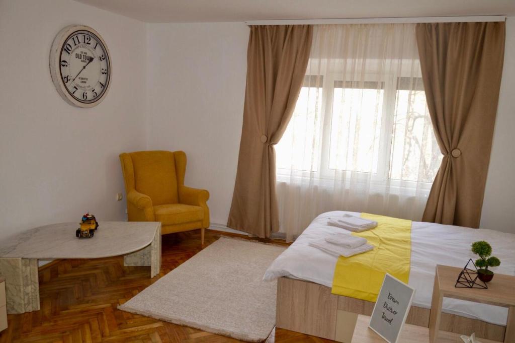 a bedroom with a bed and a chair and a clock at Joy City Stay Prefectura 1 in Timişoara