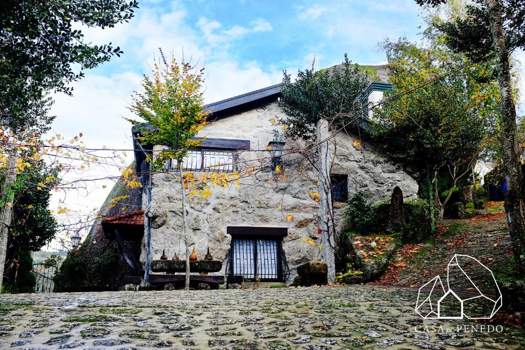 een oud stenen huis in een straat bij Casa do Penedo Gerês in Terras de Bouro