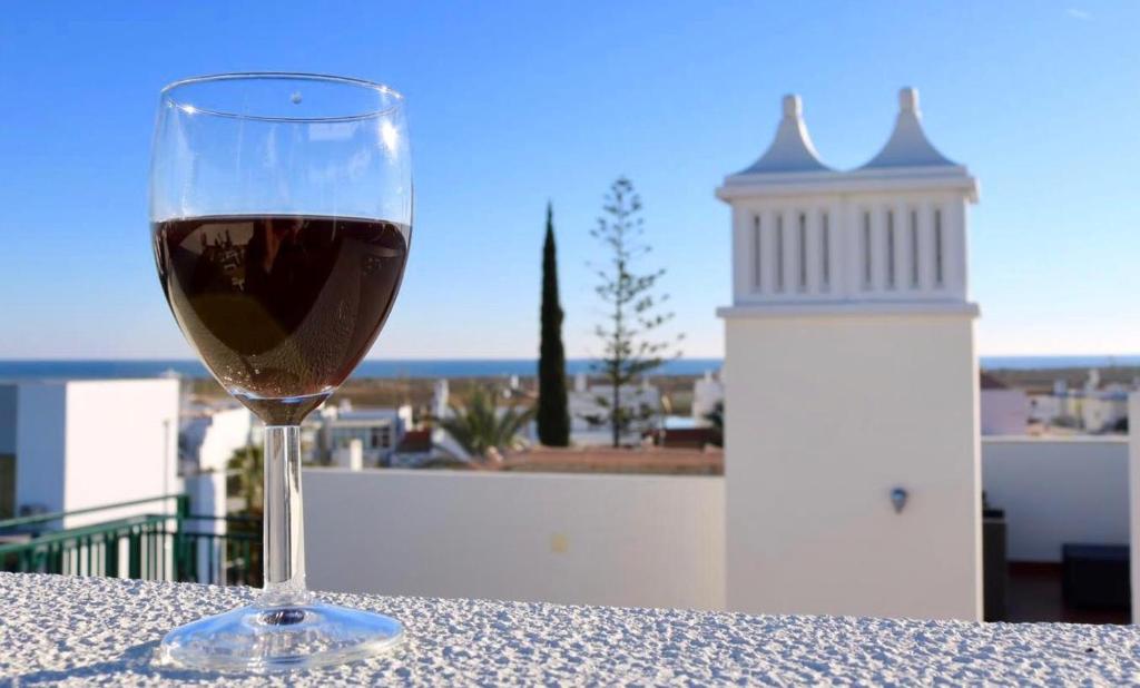 una copa de vino encima de una mesa en Central apartment-terrace and pool, en Cabanas de Tavira