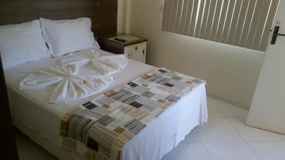 a bedroom with a bed with a white comforter at Pousada Águia in Vera Cruz de Itaparica