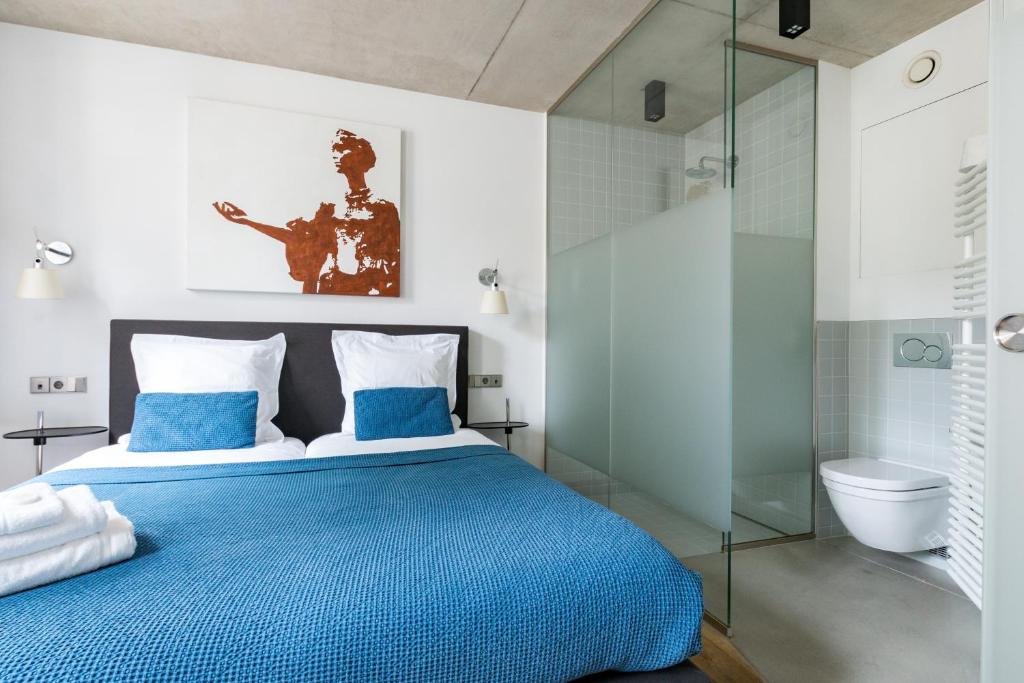 a bedroom with a blue bed and a glass shower at La Pipistrelle Hotel in Luxembourg