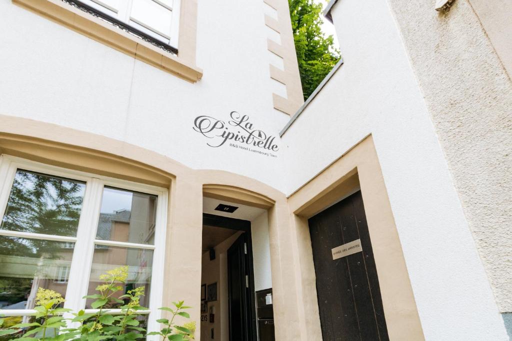 a white building with a black door at La Pipistrelle Hotel in Luxembourg