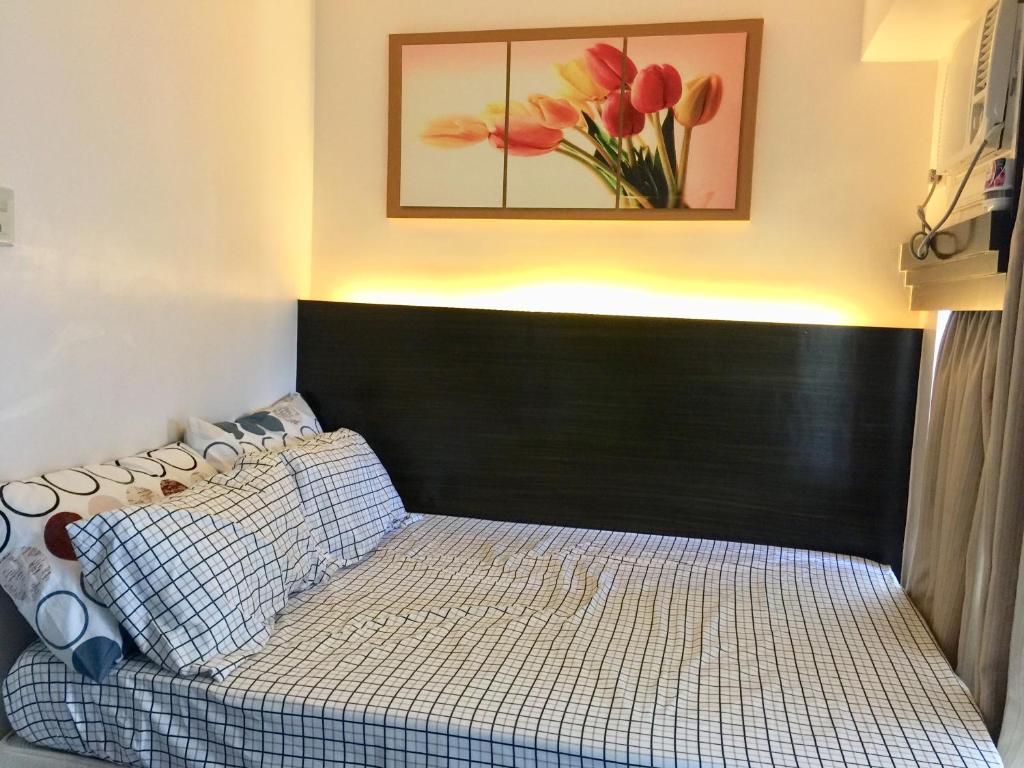een bed met een zwart hoofdeinde in een slaapkamer bij Studio Unit Cityland Prime Residence in Tagaytay