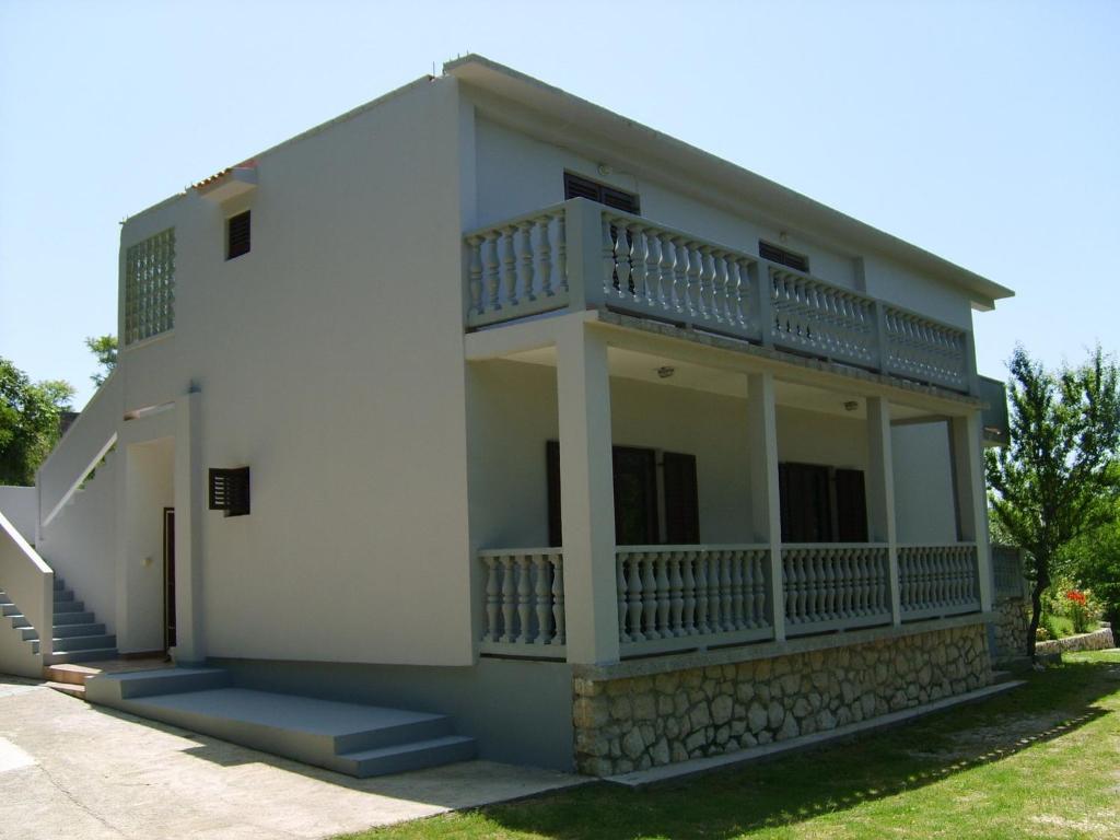 a white house with a balcony on the side at Apartment in Lopar/Insel Rab 17747 in Lopar