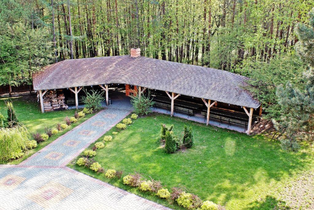 Outdoor pavilion surrounded by trees, with a pathway and green lawn.