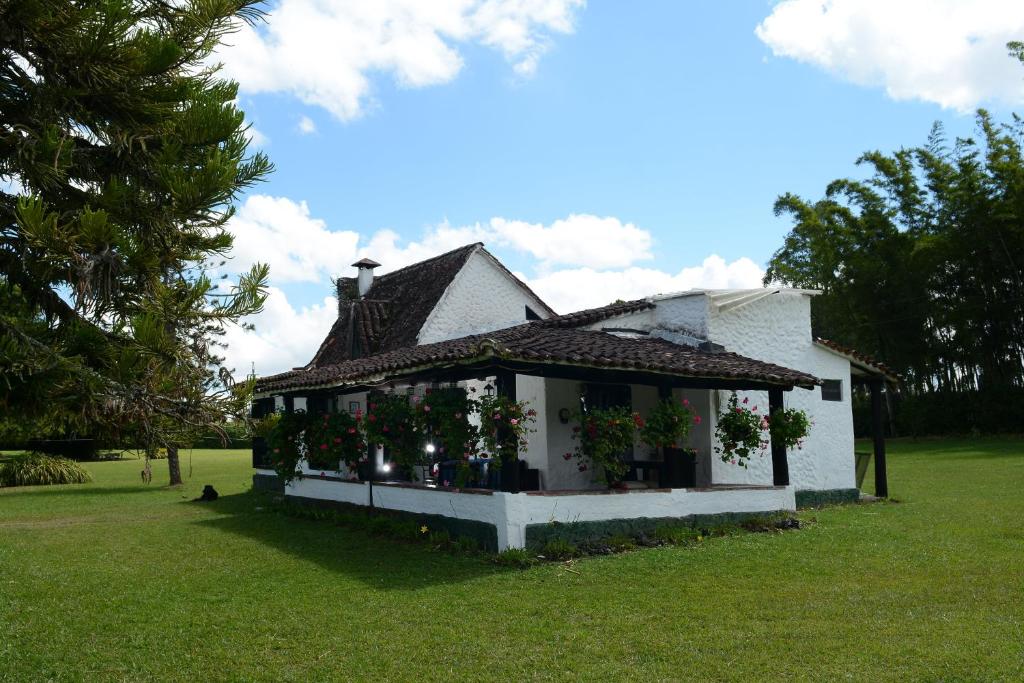 a small white house with flowers in a yard at Casa Finca Corales Llano Grande 2 in Rionegro