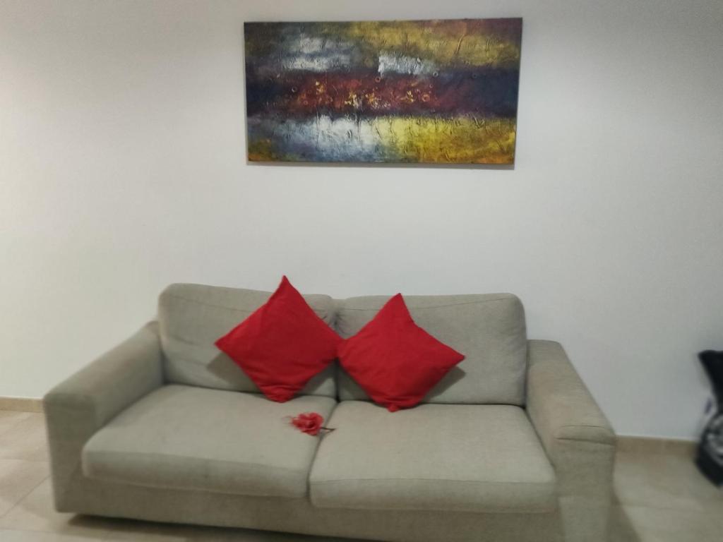 two red pillows sitting on a couch under a painting at Welcoming one bedroom apartment in Marsaskala