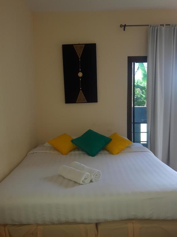 1 cama con 2 almohadas y reloj en la pared en Classic home, en Bang Tao Beach