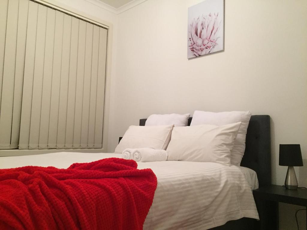a bedroom with a bed with a red blanket on it at Tasha's Apartments on Kerry in Pennington