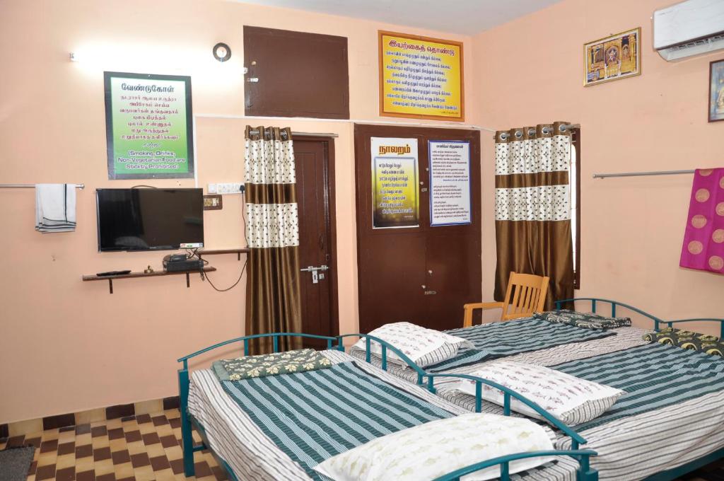 a hospital room with two beds and a tv at Homestay Senthil Akam in Chidambaram