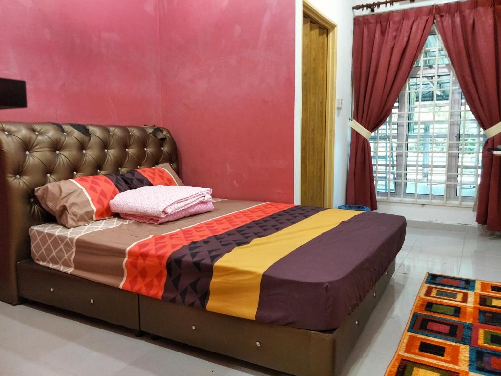 a bed in a room with a red wall at Bunga Homestay Kelantan in Bachok