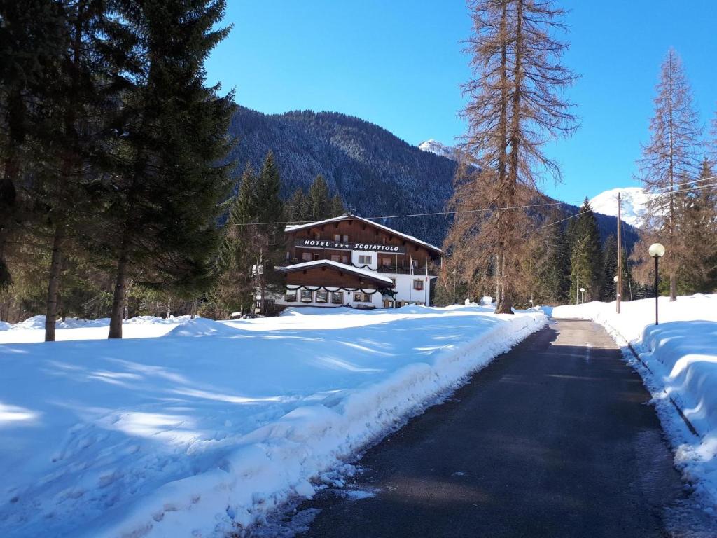 a snow covered road in front of a lodge at Albergo Scoiattolo in Falcade