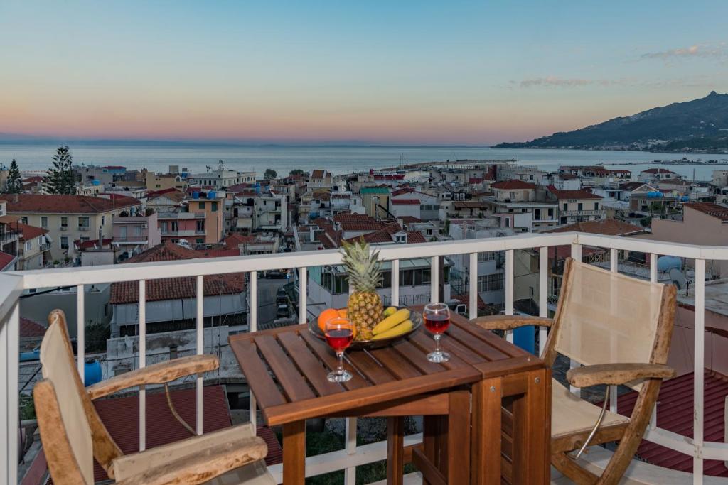 une table avec un ananas et deux verres de vin sur un balcon dans l'établissement Eolia Apartment, à Zante