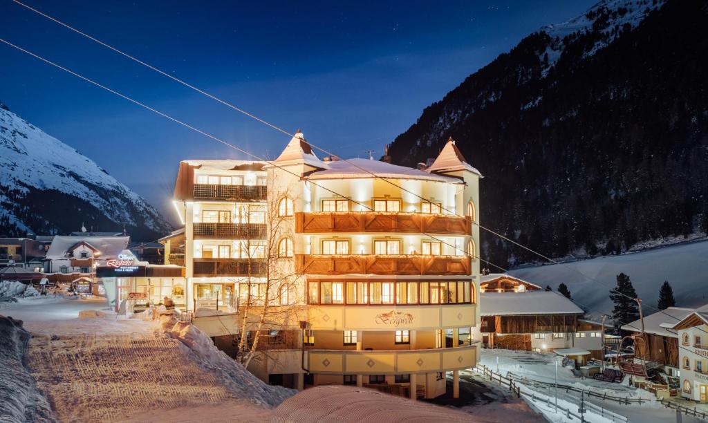 un bâtiment dans la neige devant une montagne dans l'établissement Hotel Venter Bergwelt, à Vent
