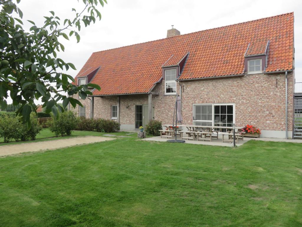 ein großes Backsteinhaus mit einem grünen Hof in der Unterkunft Holiday Home Het Verloren Goed in Wingene