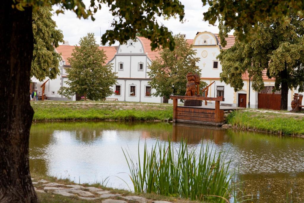 einem Teich mit einer Statue vor einem Gebäude in der Unterkunft Pension Špejchar u Vojty in Holašovice