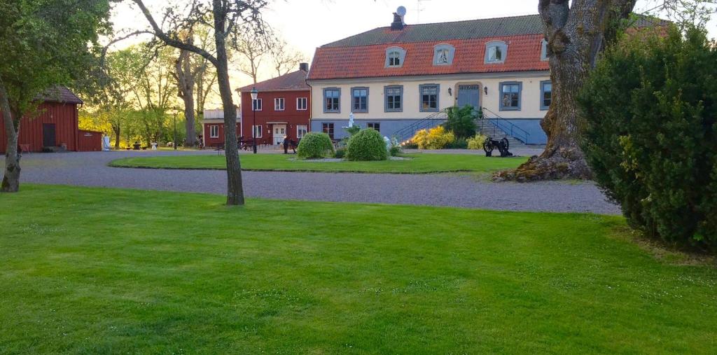 uma grande casa branca com um telhado vermelho em Brunsbo G:a Biskopsgård Hotell & Konferens em Skara